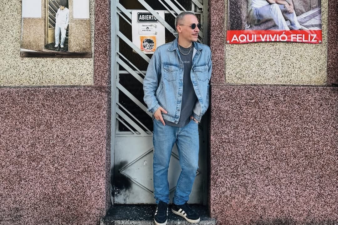 Pedro Hackbarth em frente a fachada de prédio com arte urbana e cartaz cultural
