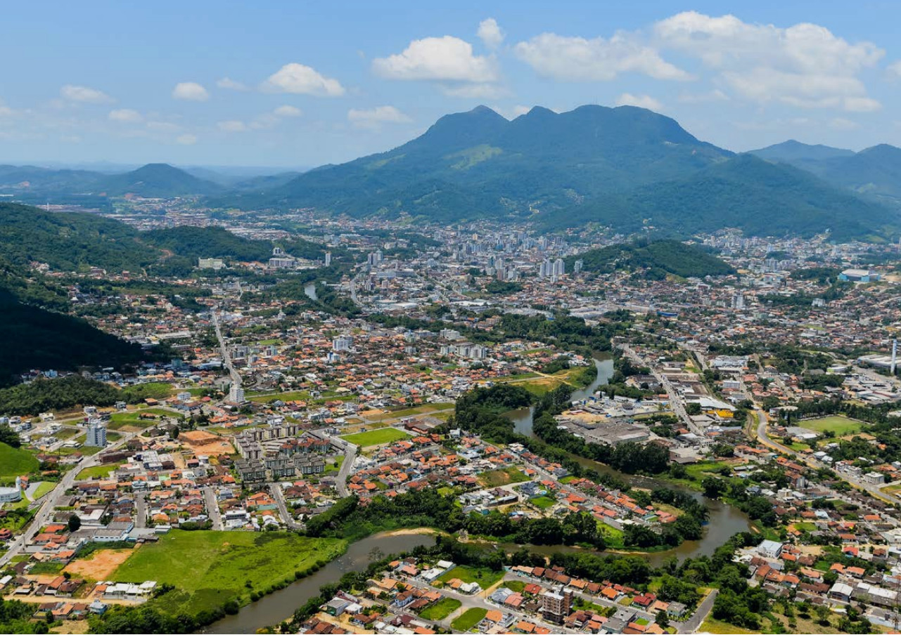 Vista aérea de Jaraguá do Sul com áreas urbanas, rio e regiões de expansão imobiliária