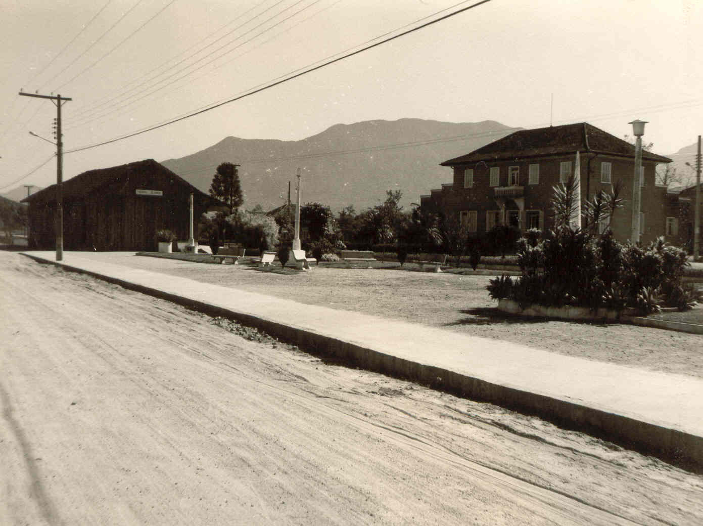 Imagem antiga a praça do bairro Nereu Ramos, em Jaraguá do Sul, com casas históricas e rua sem pavimentação