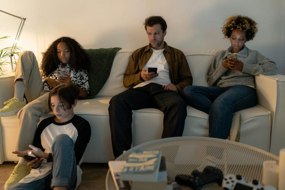 Família reunida no sofá utilizando celulares sem interação entre si