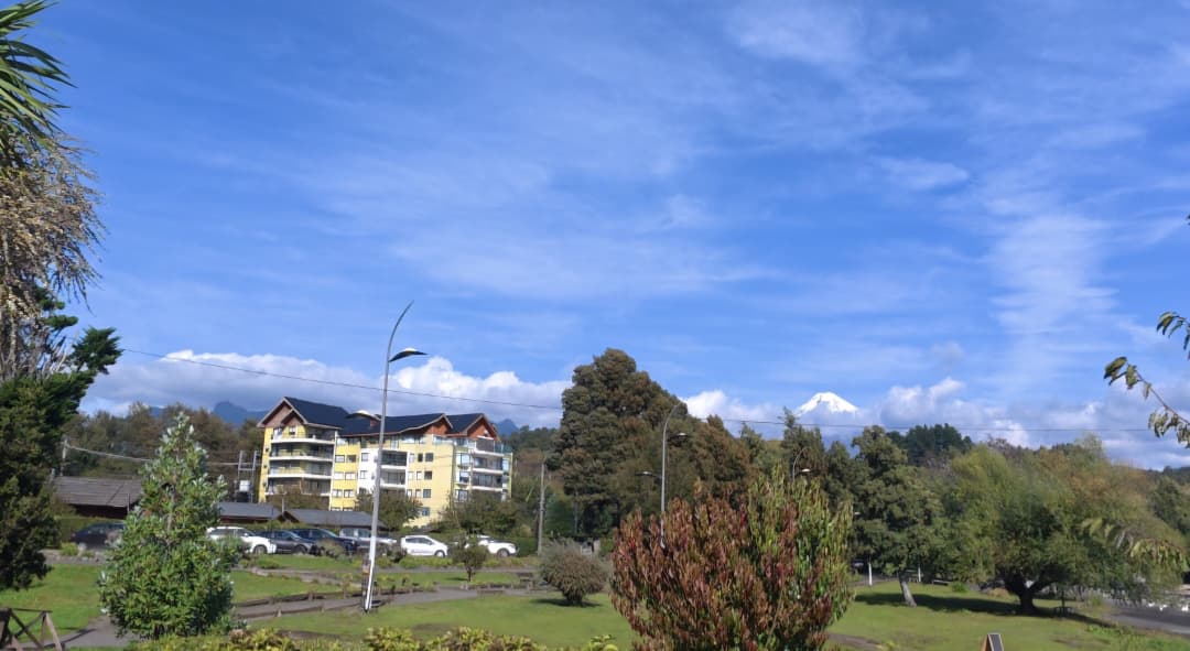 Vista do vulcão Villarrica em Pucón no Chile cercado por áreas verdes e céu limpo