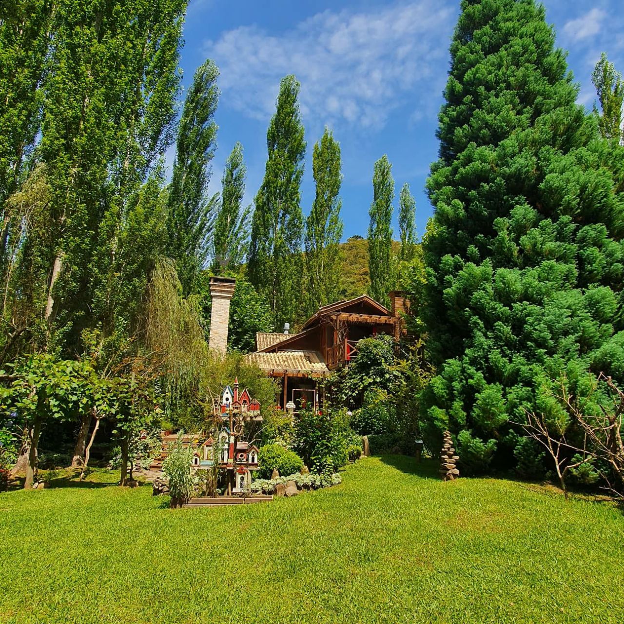 Área ajardinada com árvores ornamentais e construção em estilo europeu no Jardim Secreto Ville de France.