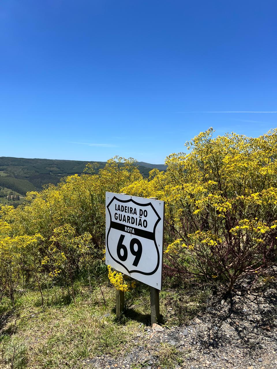 Placa da Rota 69 em Alfredo Wagner cercada por montanhas e vegetação na Serra Catarinense