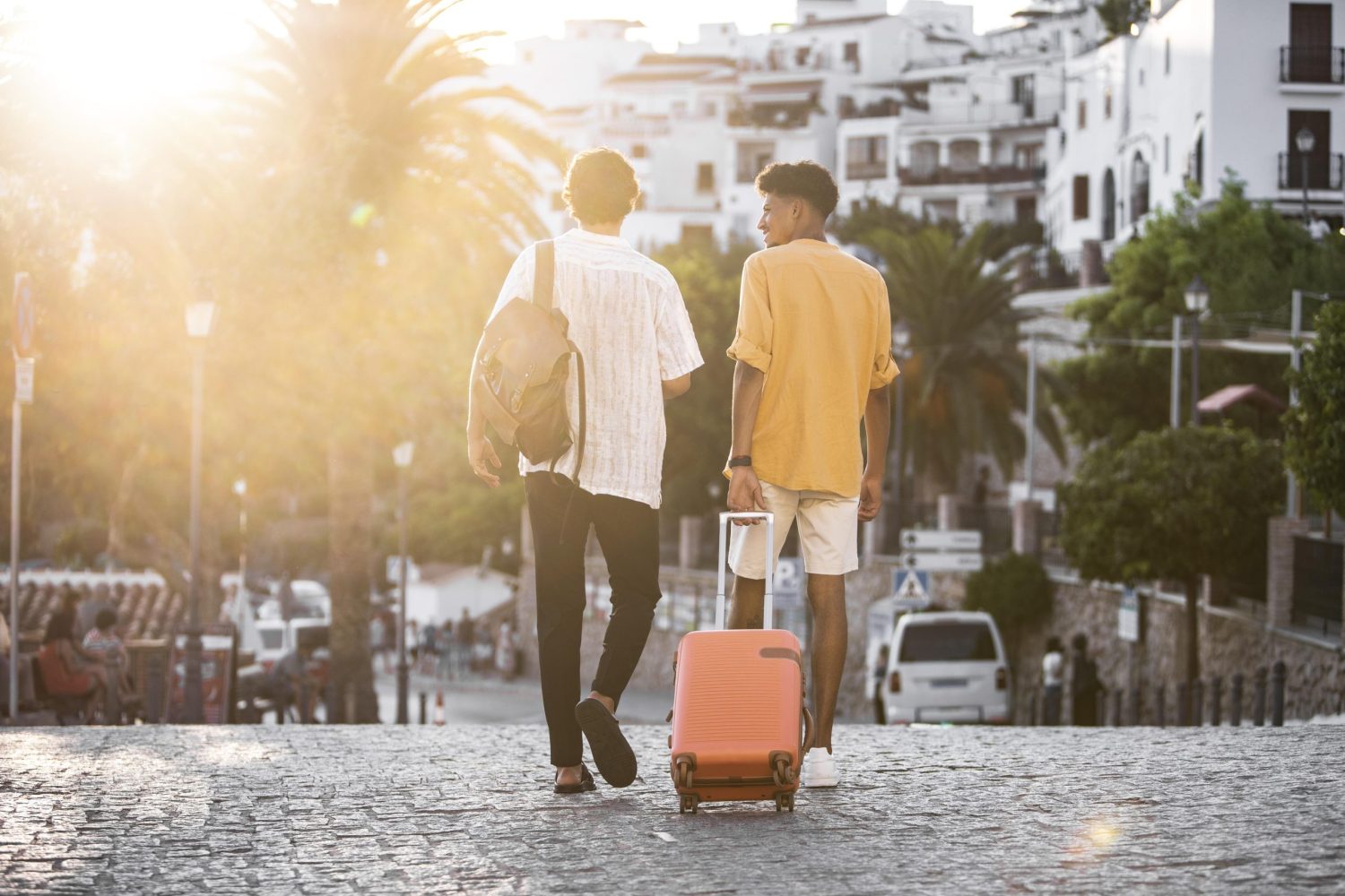 Turistas caminham por rua de destino ensolarado com mala de viagem