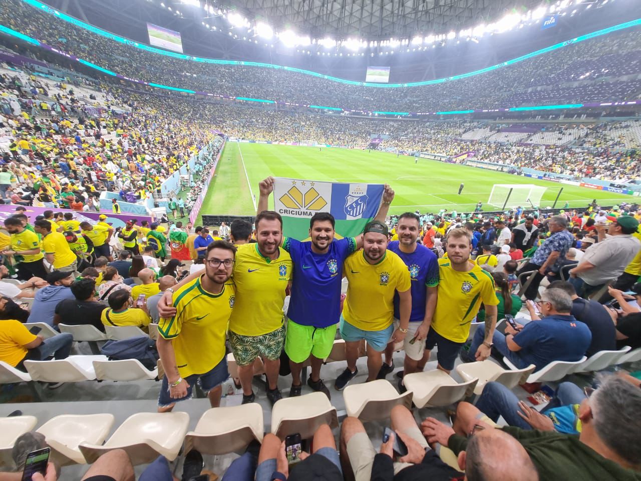Grupo de torcedores brasileiros em estádio da Copa do Mundo do Catar acompanhando partida do Mundial.