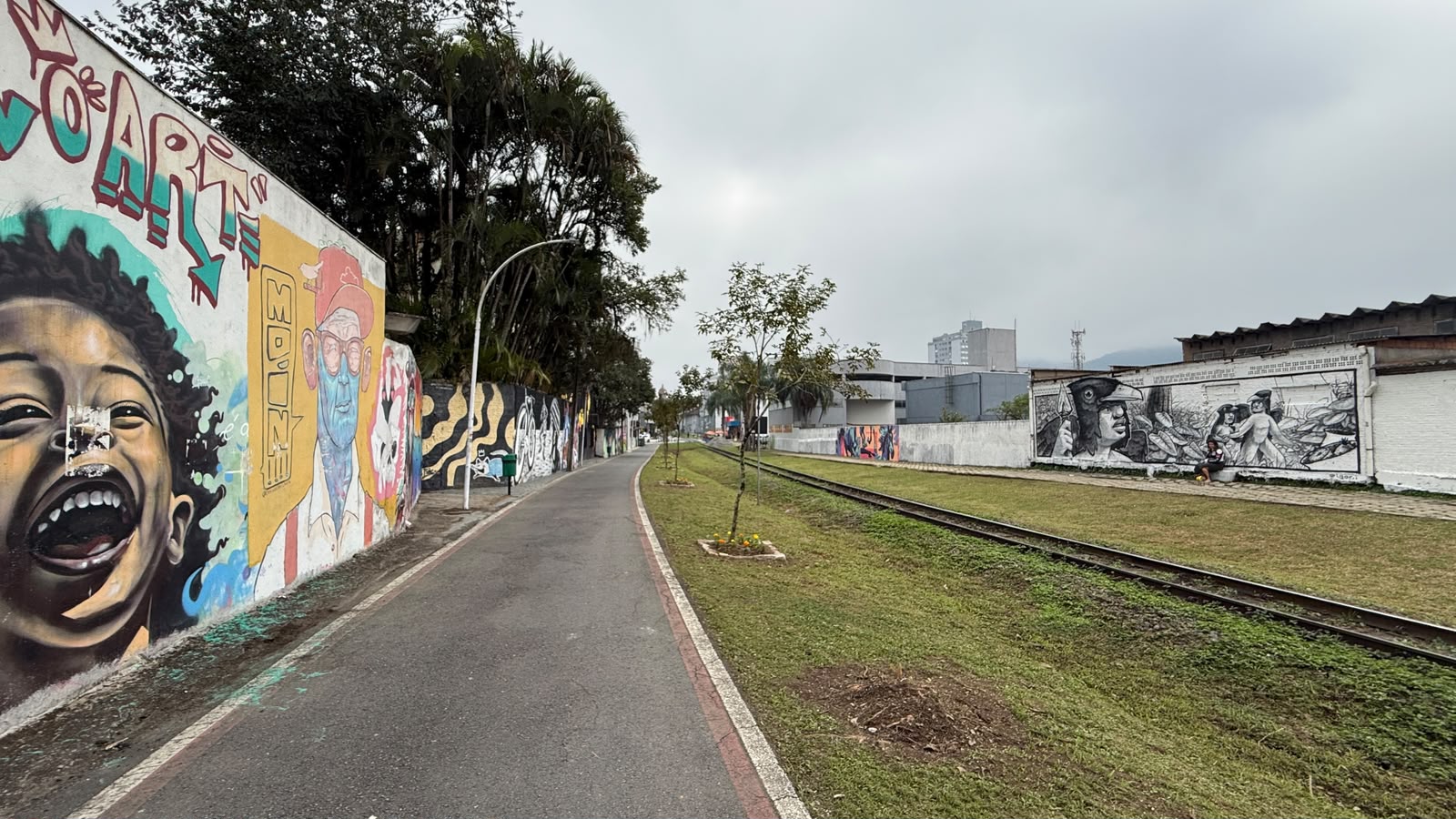Vista do Caminho das Artes na ciclovia do Centro de Jaraguá do Sul, com murais ao lado da linha férrea.